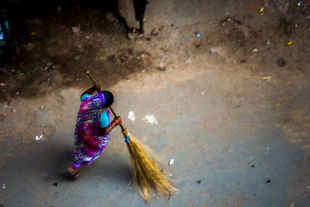 An Indian woman sweeping the dirty streets of Kolkata with a broom