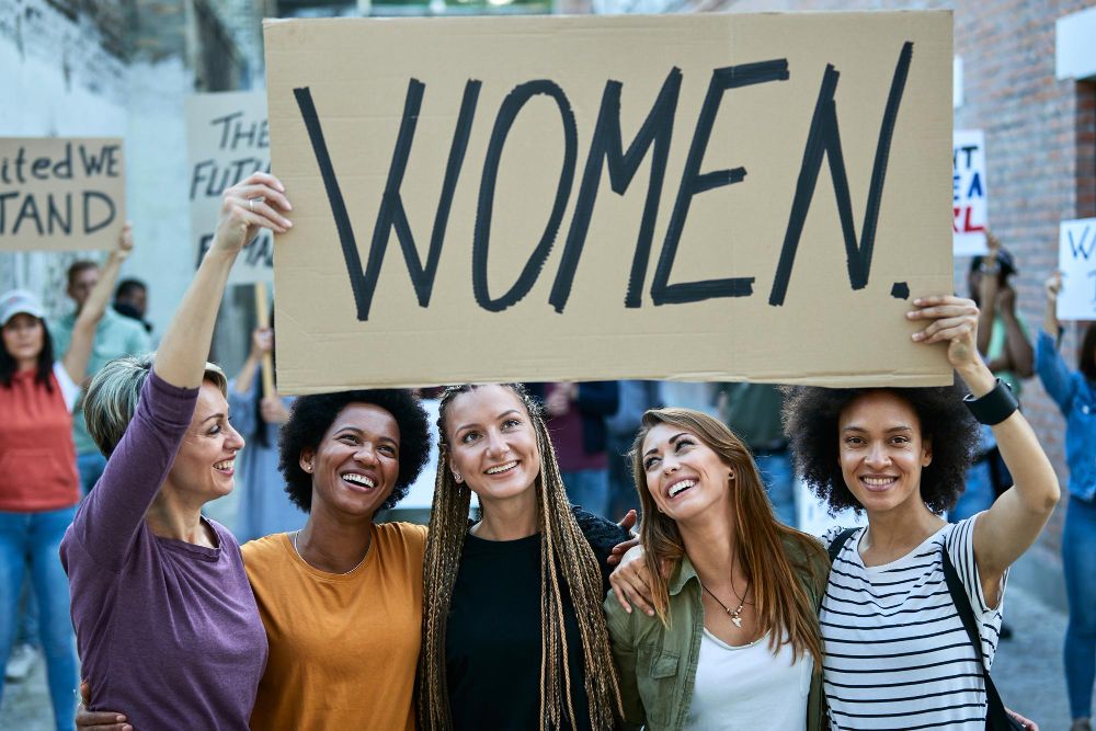 A diverse group of women holding a board titled “women”