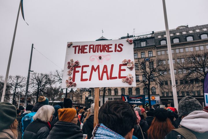 People protesting on the road with a placard saying "The Future is Female"